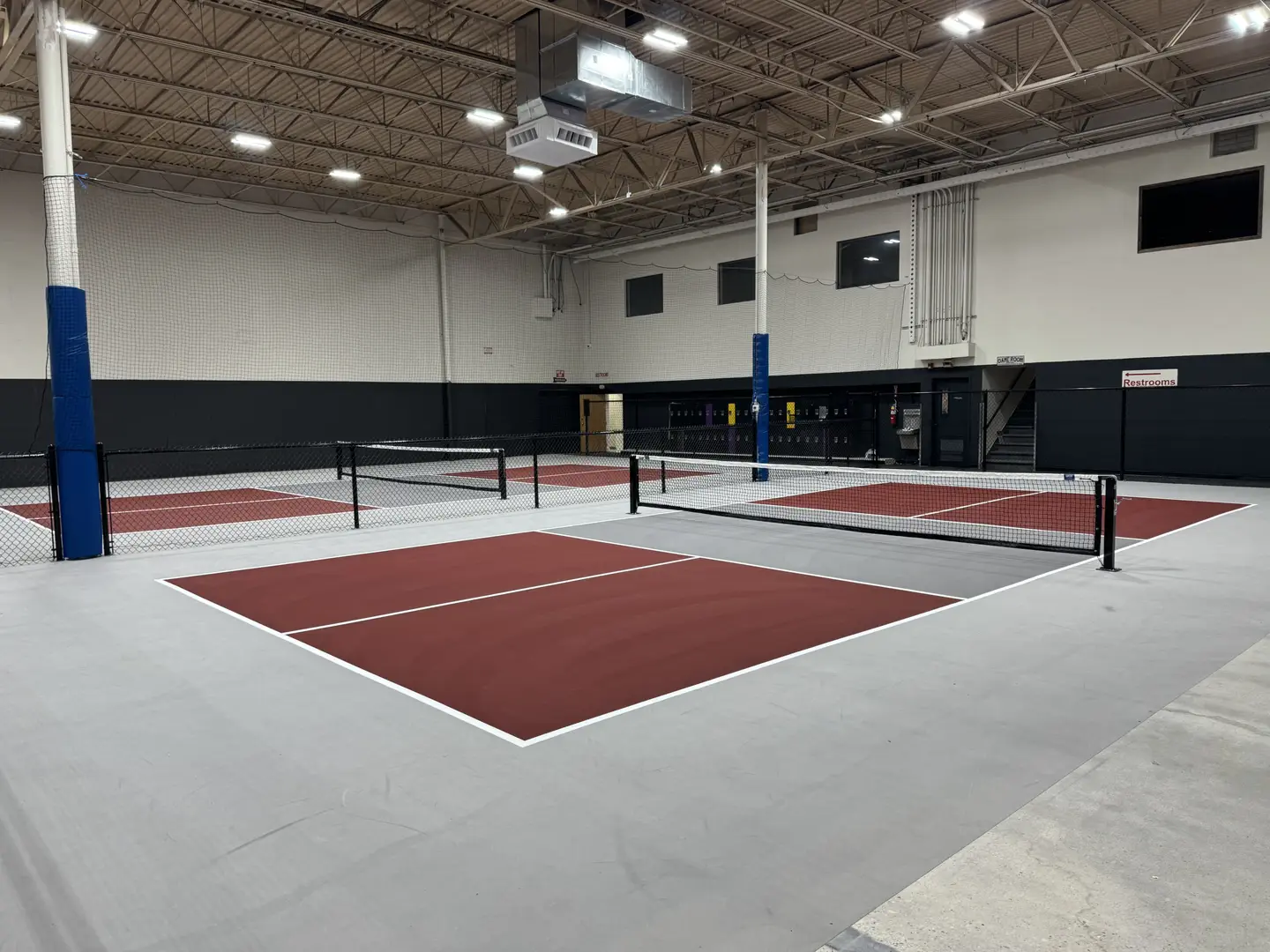 Indoor pickleball courts with red playing surfaces and nets.