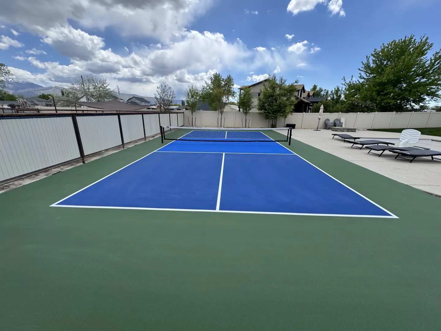 Vibrant blue pickleball court with green surround and white lines.