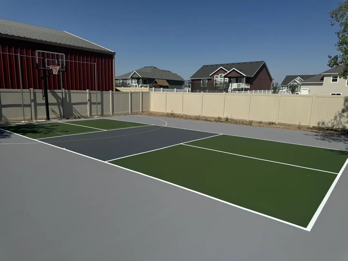 Multi-sport court with basketball hoop in a residential backyard.