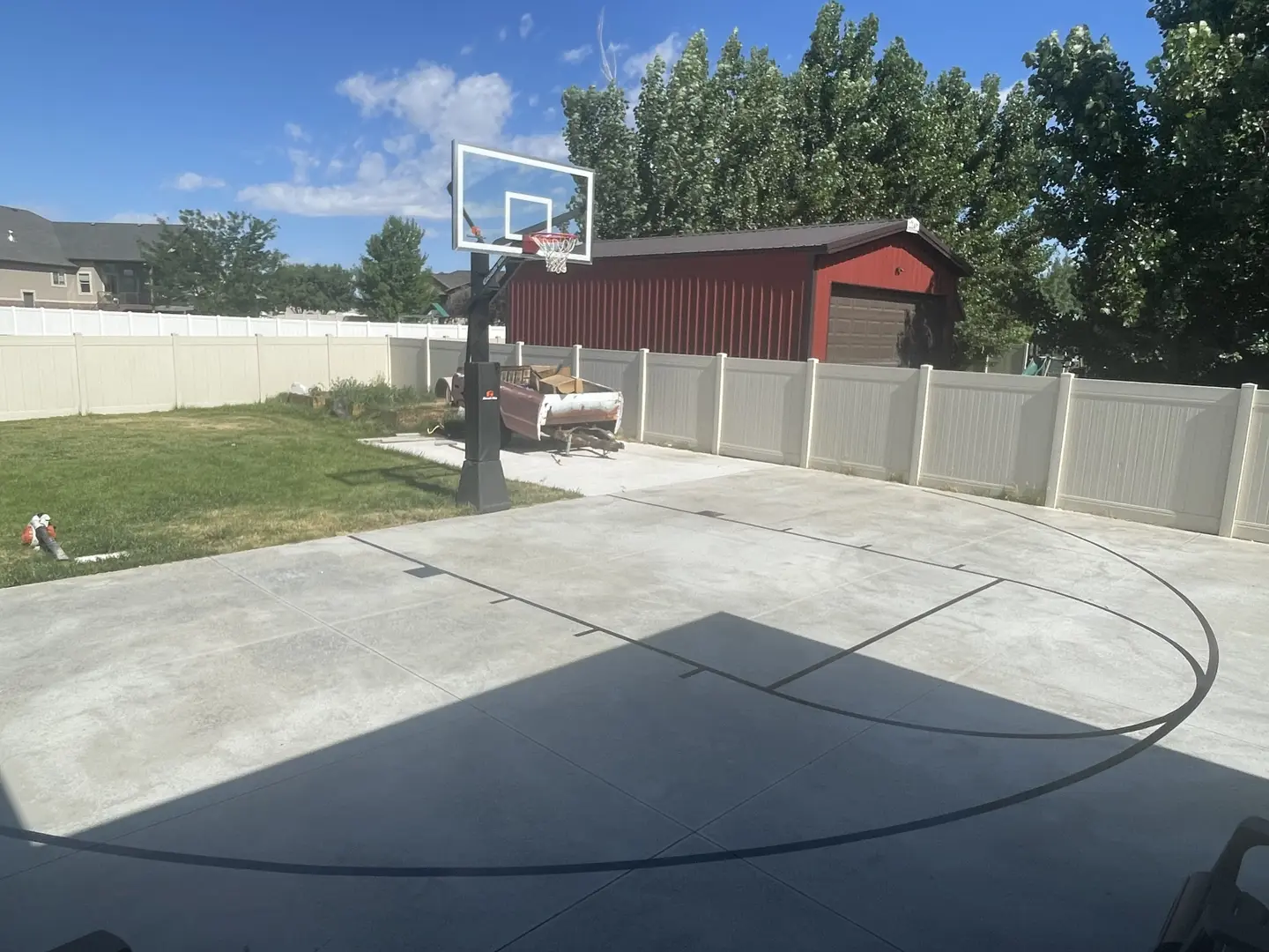 Backyard basketball court with a hoop and a red shed.