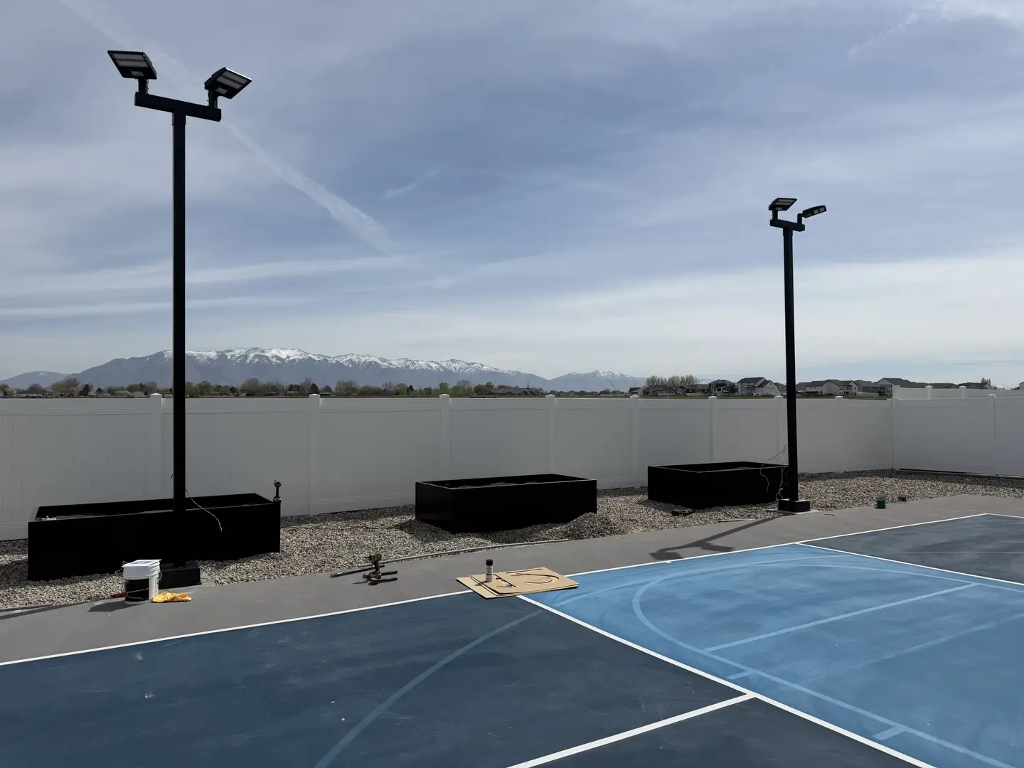 Outdoor basketball court lighting installation with mountain backdrop