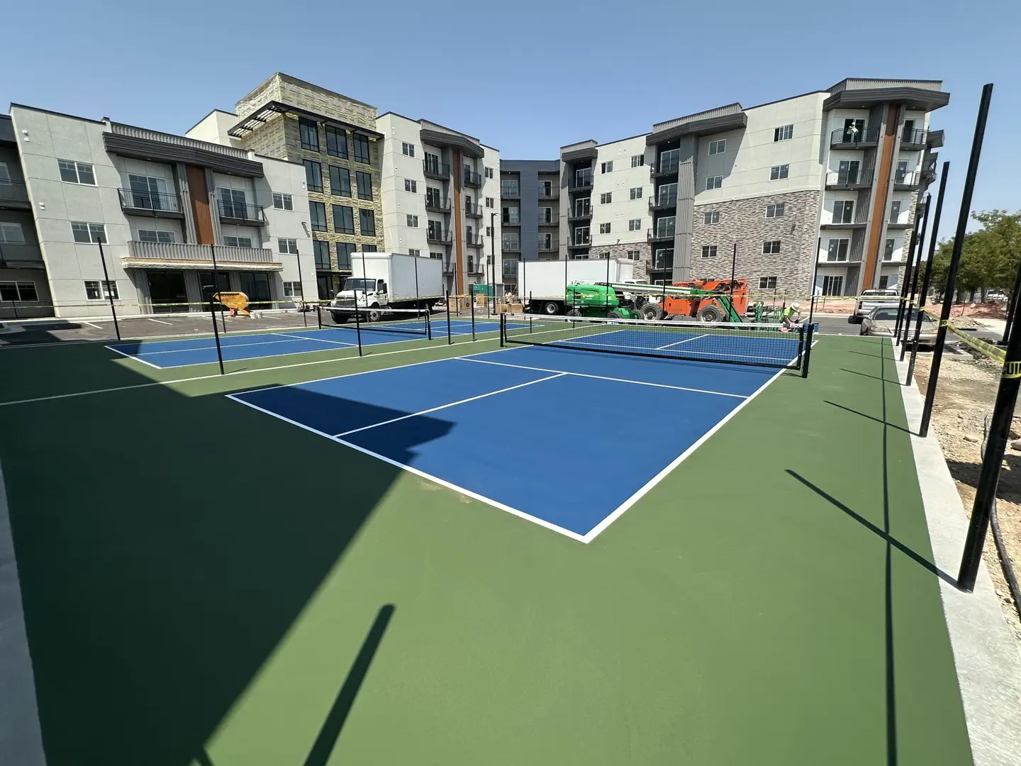 Newly constructed pickleball courts next to an apartment building.