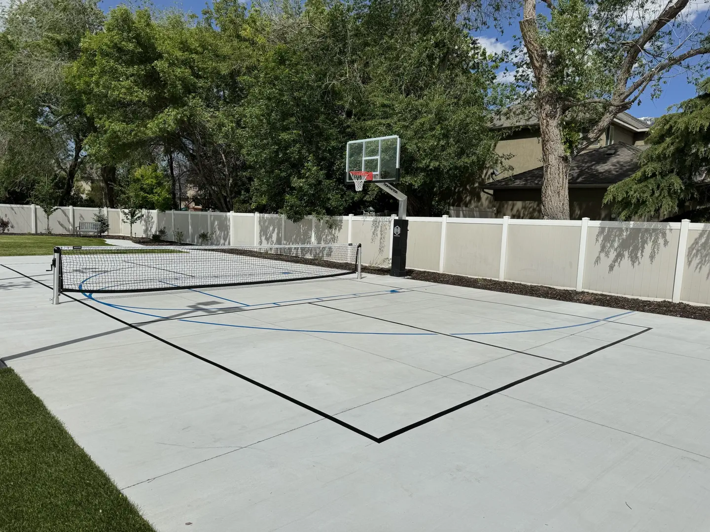 Backyard multi-sport court with basketball hoop and pickleball lines