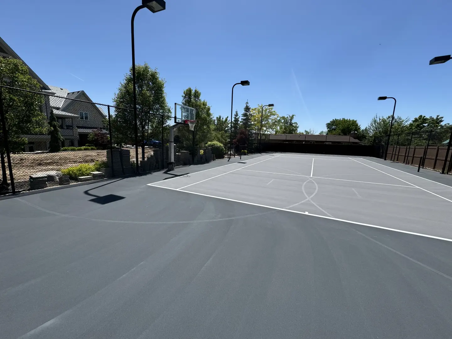 Outdoor multi-sport court with basketball hoop and tennis lines