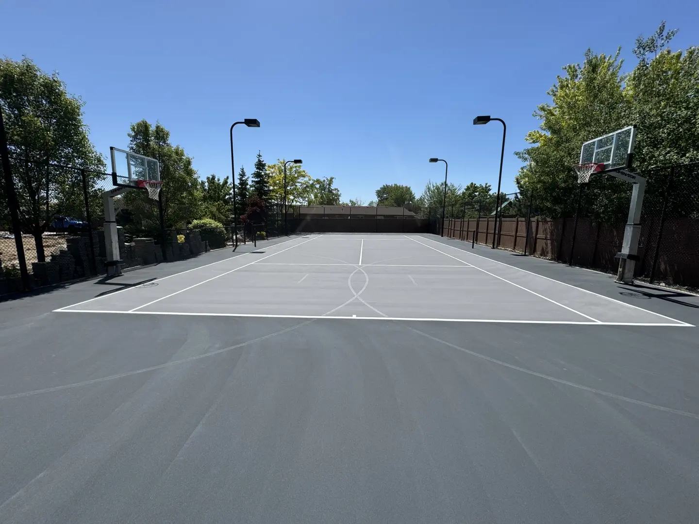 Outdoor basketball court with two hoops and lighting.