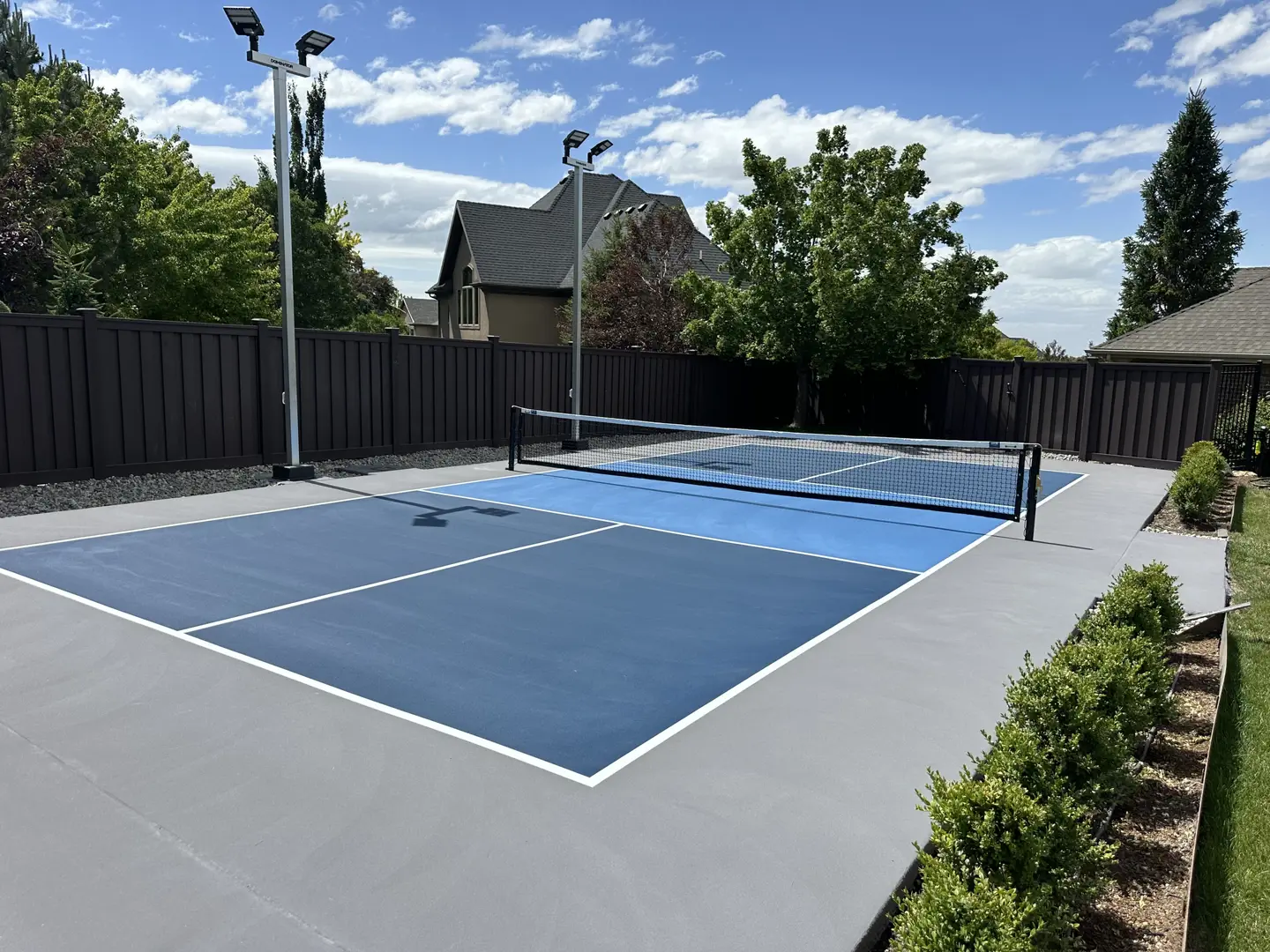 Outdoor pickleball court with blue surface and lights