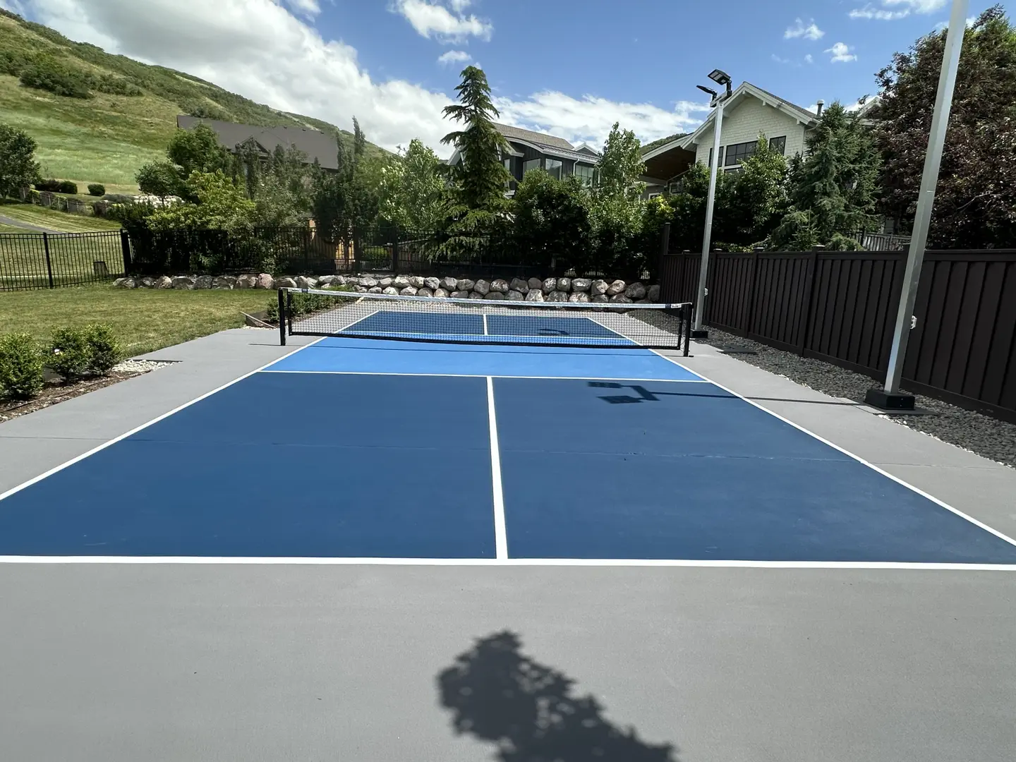 Blue pickleball court with net and surrounding fence