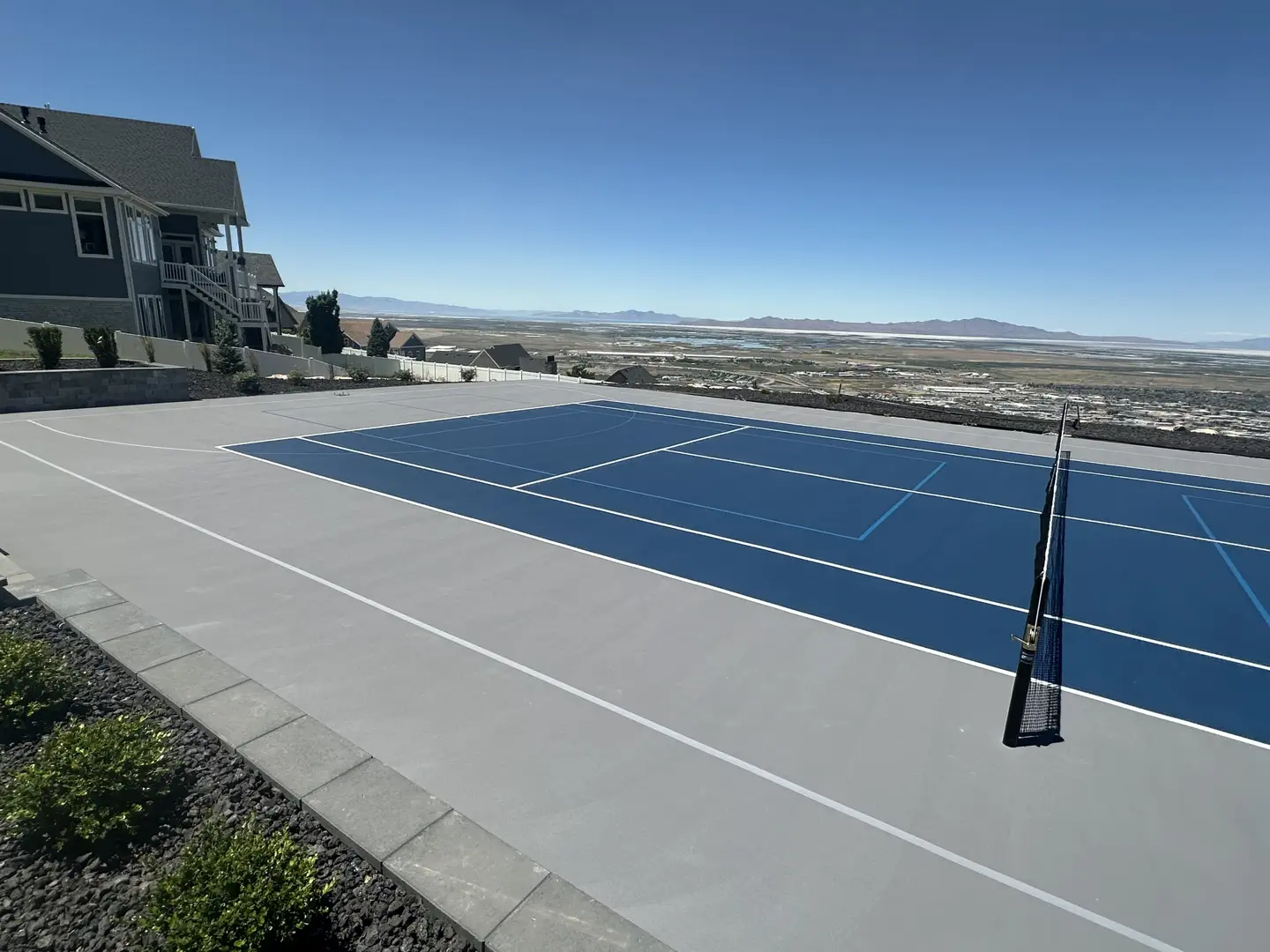 Blue tennis court with a scenic mountain view in the distance.