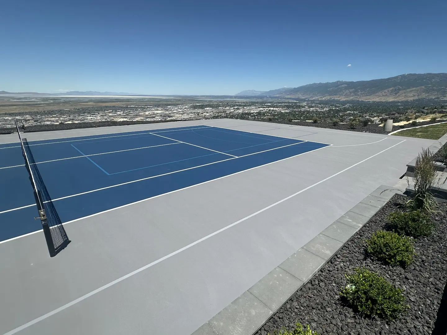 Blue tennis court with a scenic mountain and valley view.