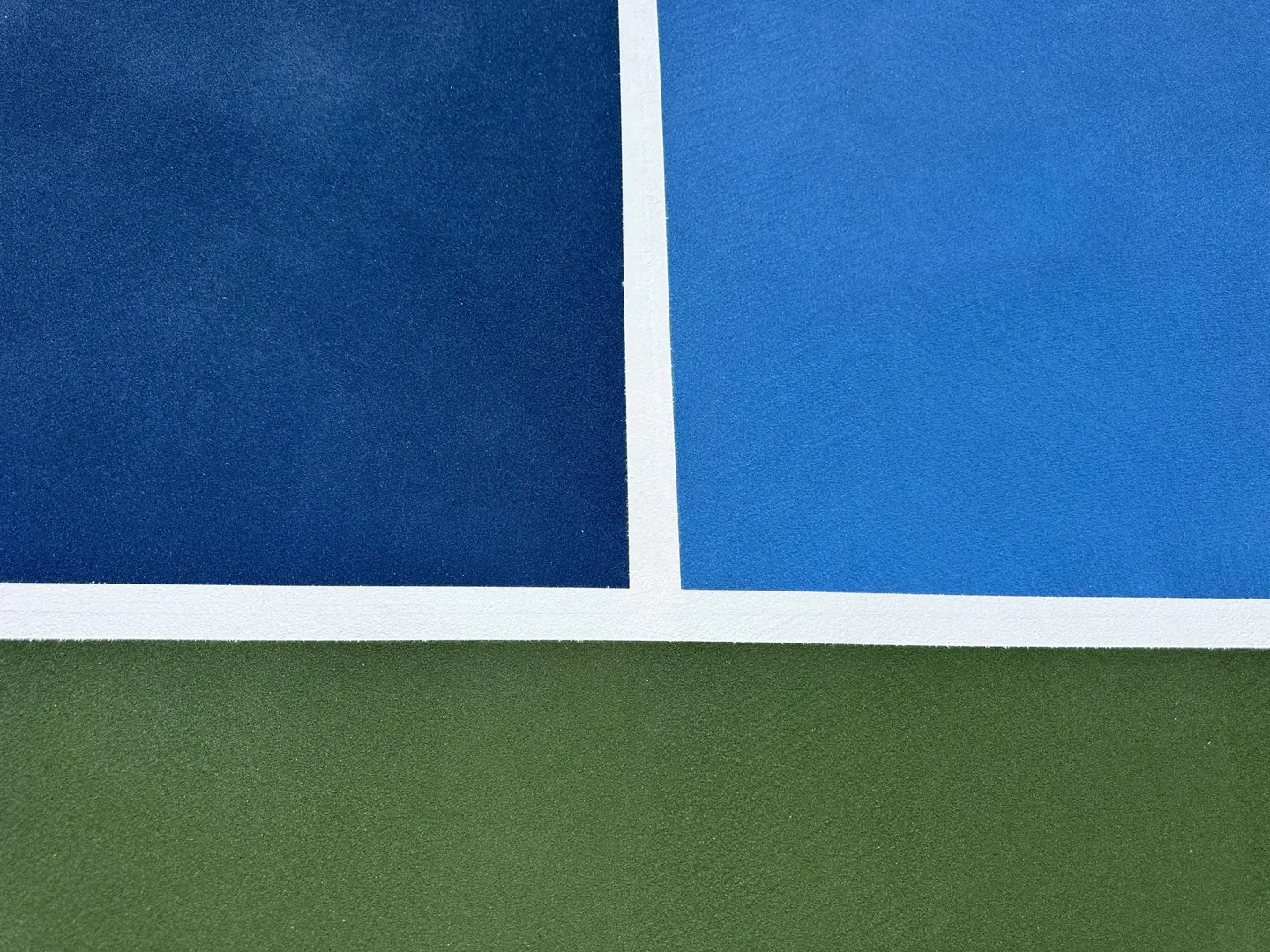Close-up of a blue and green tennis court surface with white lines.