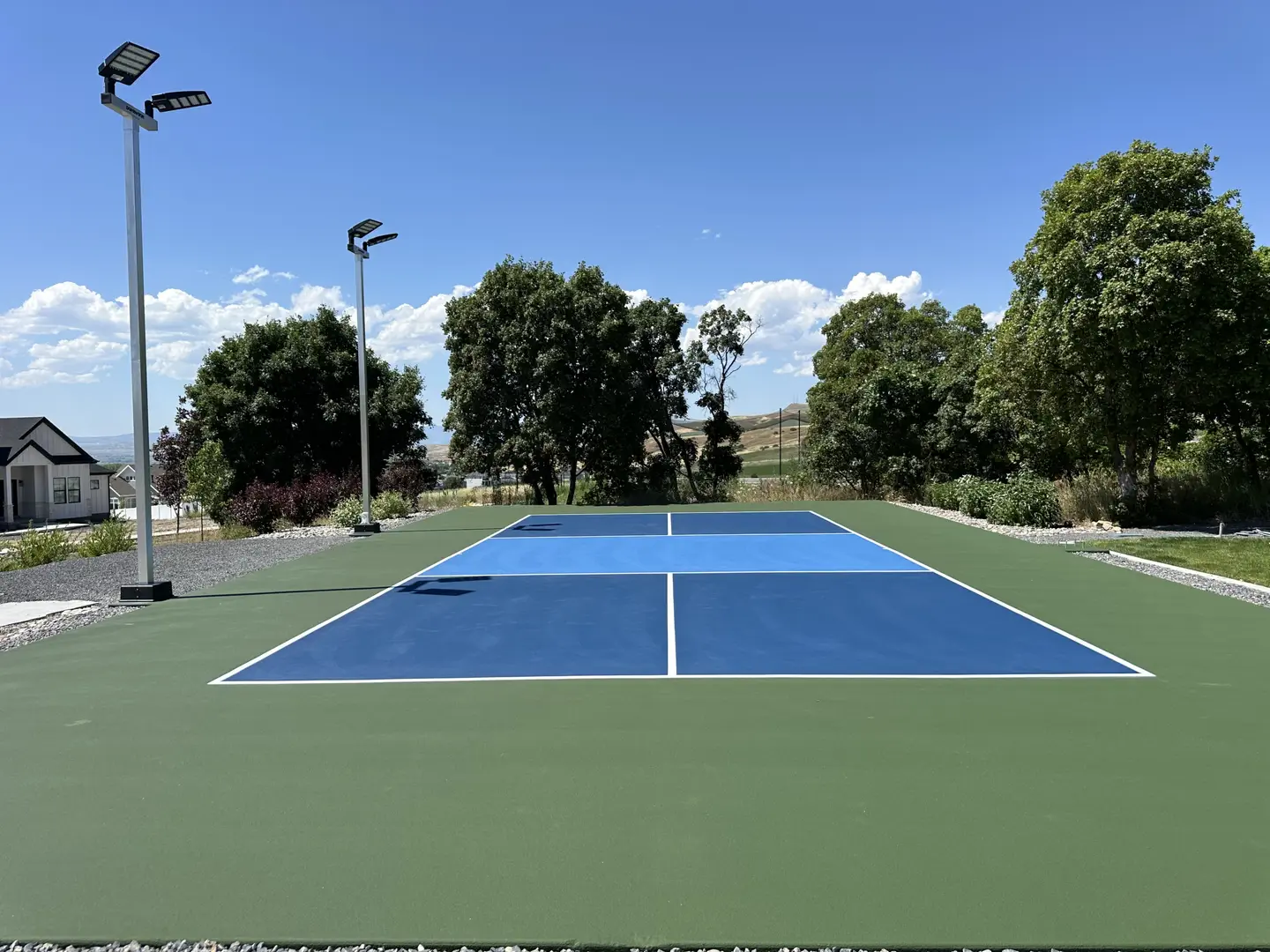 New outdoor pickleball court with blue and green surfacing and lighting.