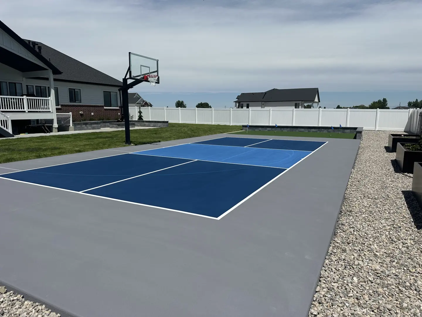 Multi-sport court with basketball hoop in a suburban backyard.