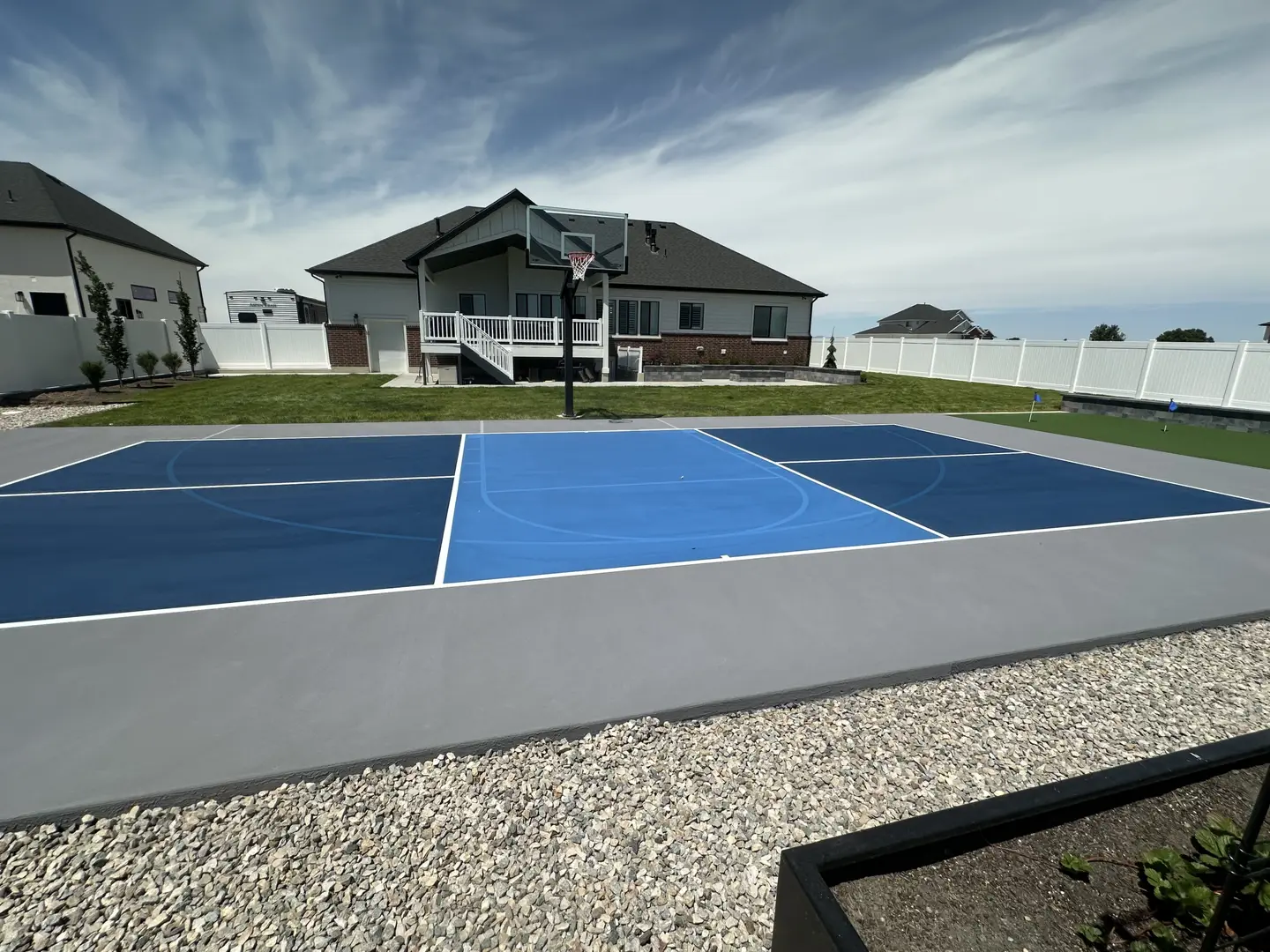 Modern backyard basketball court with blue and dark blue playing surface.