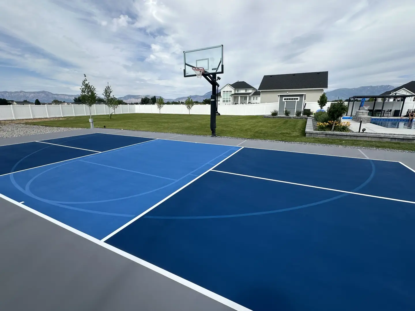 Custom blue basketball court in a backyard with mountains in the background.